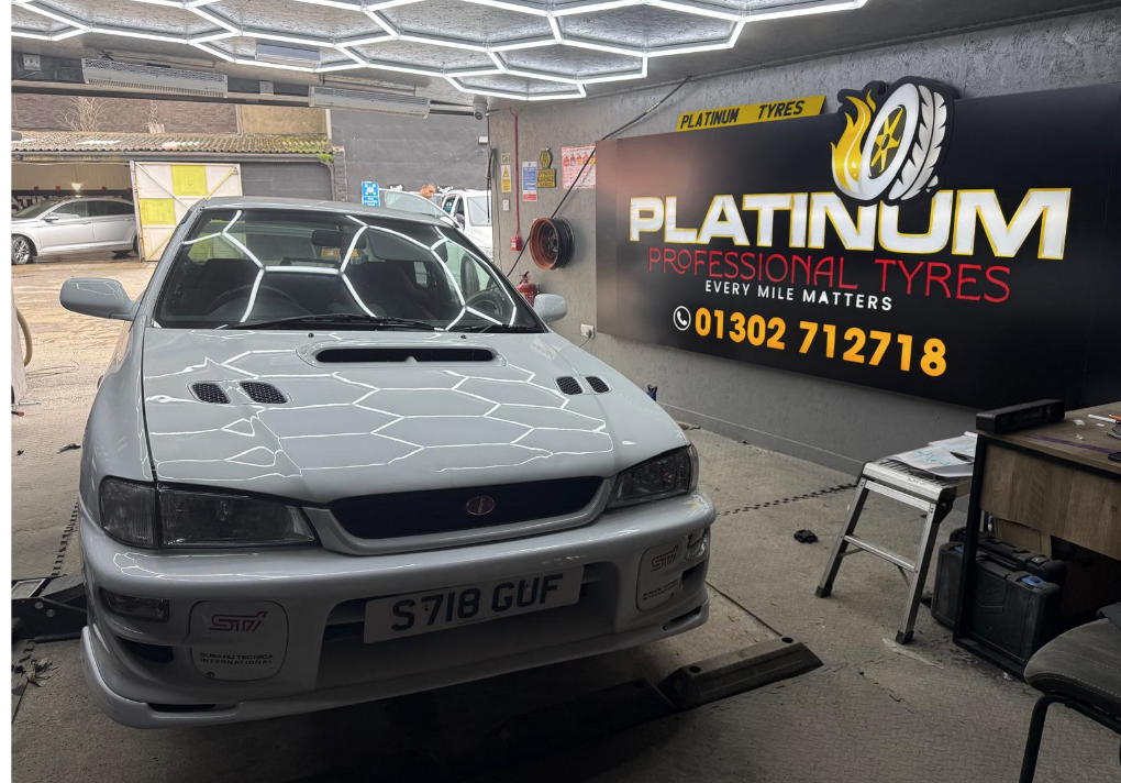 White car inside the Platinum Tyres workshop under hexagonal LED lights
